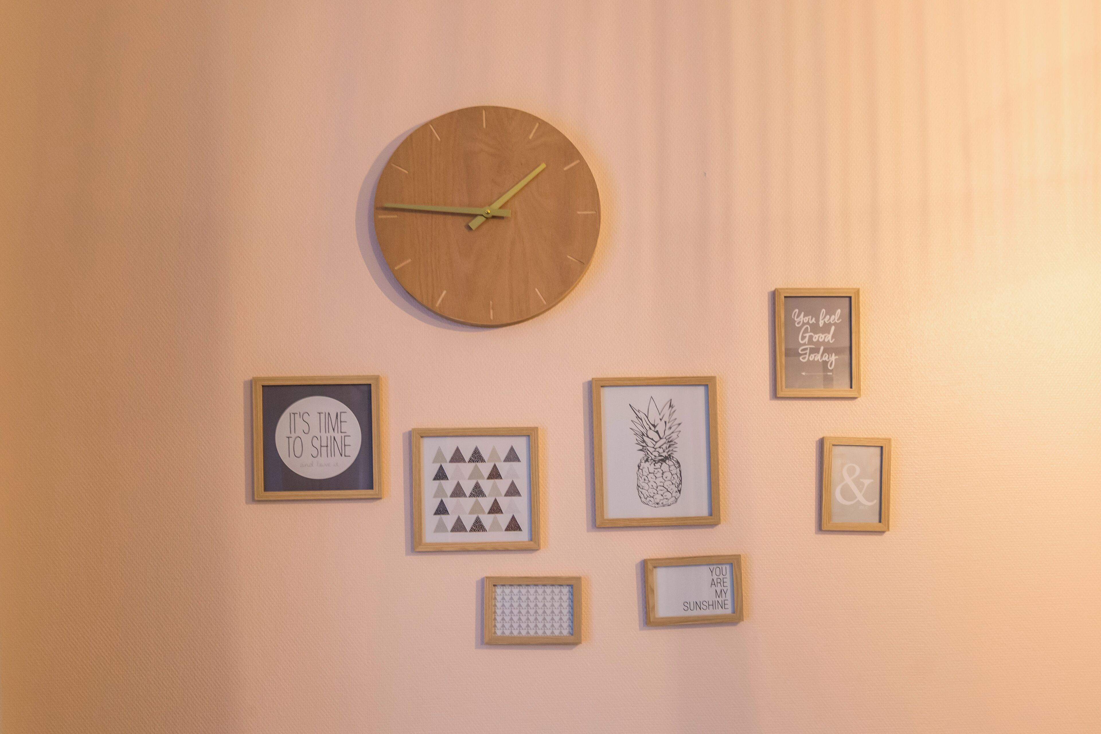 Un mur orné d’une horloge et de plusieurs tableaux encadrés.