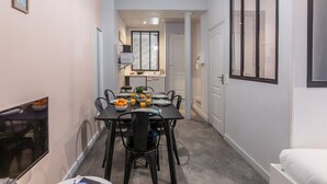 A narrow hallway with a dining area featuring a table set with plates, bowls, and a fruit bowl.