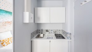 Cozinha compacta com bancada branca, pia e armário acima.