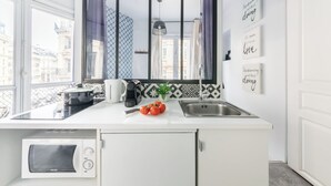 A modern kitchen with a built-in microwave, a sink, and a window overlooking a cityscape. - WS Louvre - Etienne Marcel (Paris)