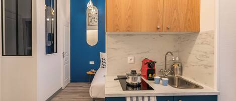 A compact kitchen with a sink, a stove, and a coffee maker.