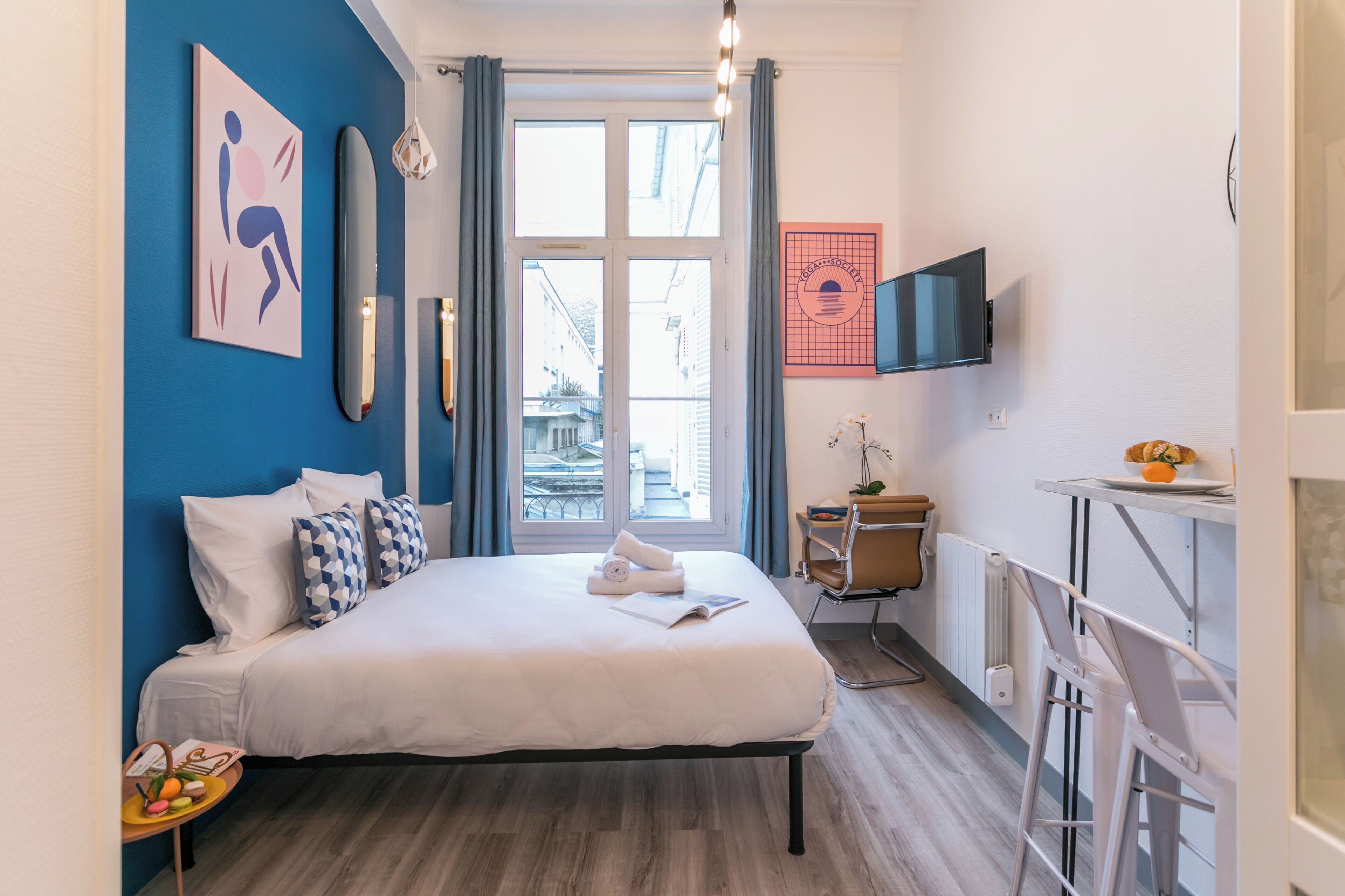 Een moderne hotelkamer met een groot bed, een bureau, een televisie en een raam met gordijnen.