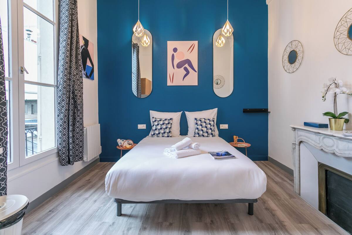A modern bedroom with a large bed, a fireplace, and artwork on the walls.