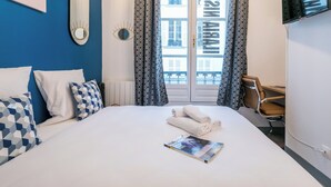 Une chambre d’hôtel avec un lit, des oreillers, un magazine, une chaise et un téléviseur.