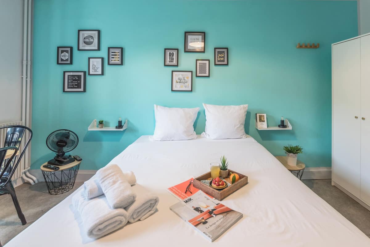 A neatly made bed with white linens, a tray of breakfast items, and a magazine on the bed.