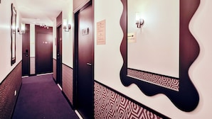 A hotel hallway with patterned walls, a carpeted floor, and doors numbered 101 and 103. - WS Nation - Reuilly (Paris)