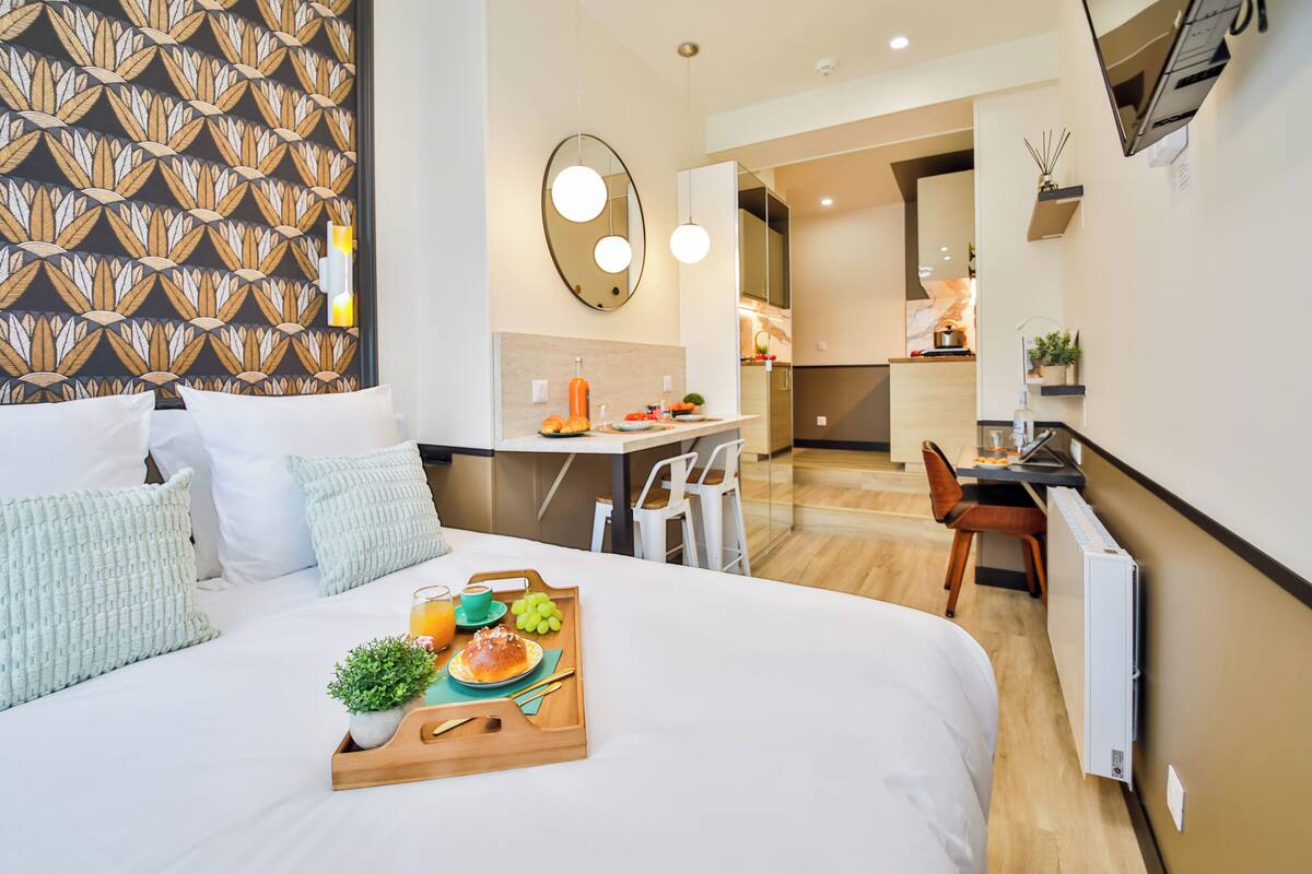 Habitación de hotel con cama, bandeja de desayuno y escritorio con silla.
