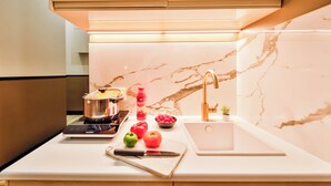 Una cocina moderna con salpicadero de mármol, estufa integrada, lavamanos y encimera con verduras frescas.