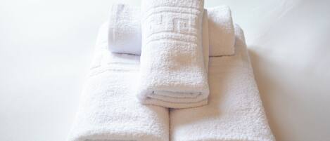 Three neatly folded white towels stacked on a white surface.