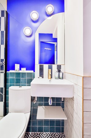 Une salle de bain moderne avec un lavabo blanc, des carreaux bleus et des toilettes.