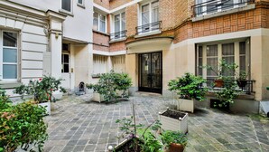 A courtyard with a brick and plaster facade, potted plants, and a tiled floor. - WS Champs-Elysées - Daru (Paris)