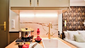 A modern kitchen with a stove, a sink, and a countertop with a cutting board and tomatoes. - WS Champs-Elysées - Daru (Paris)