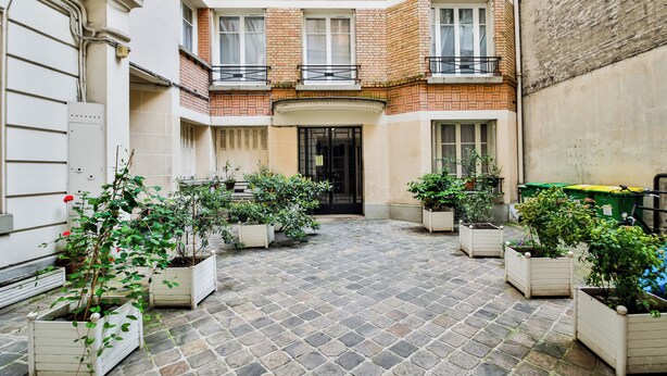 A courtyard with potted plants and a brick building. - WS Champs-Elysées - Daru (Paris)