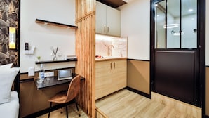 A compact kitchen with a wooden partition, a dining area with a chair, and a black-framed door. - WS Champs-Elysées - Daru (Paris)