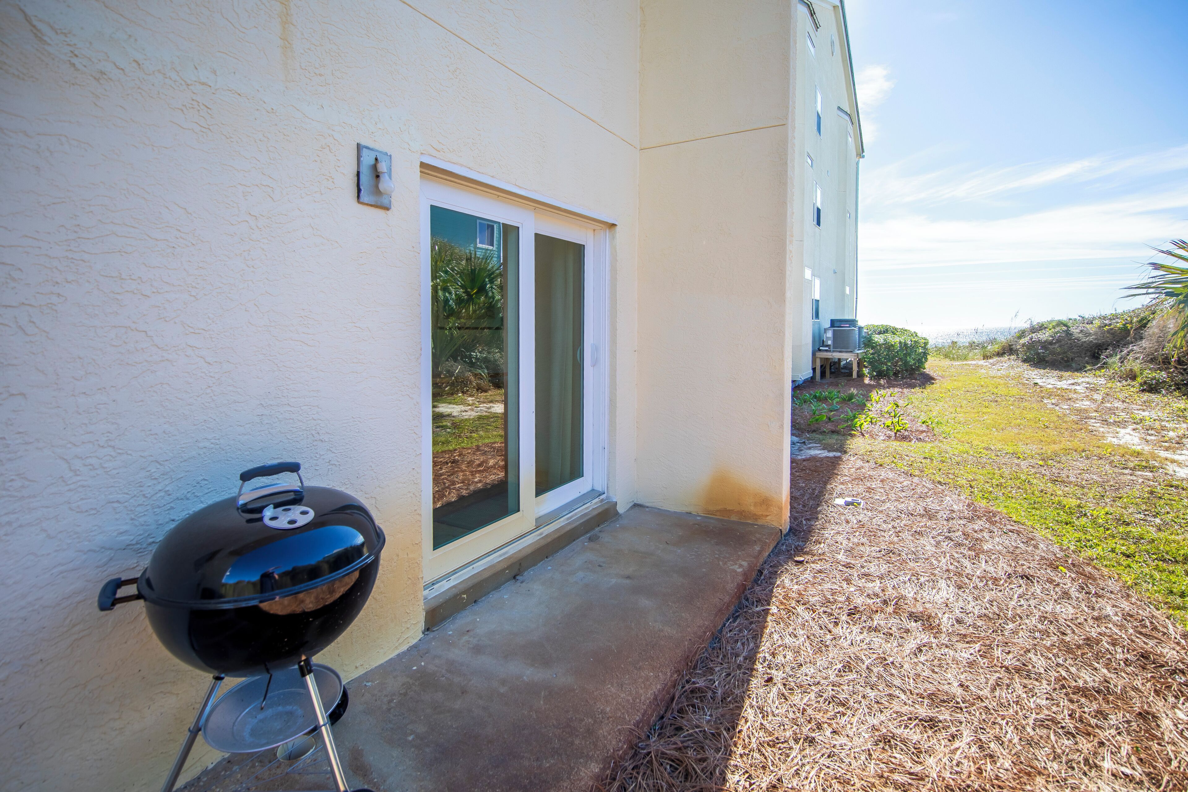 A barbecue grill outside a house with a door and a window.