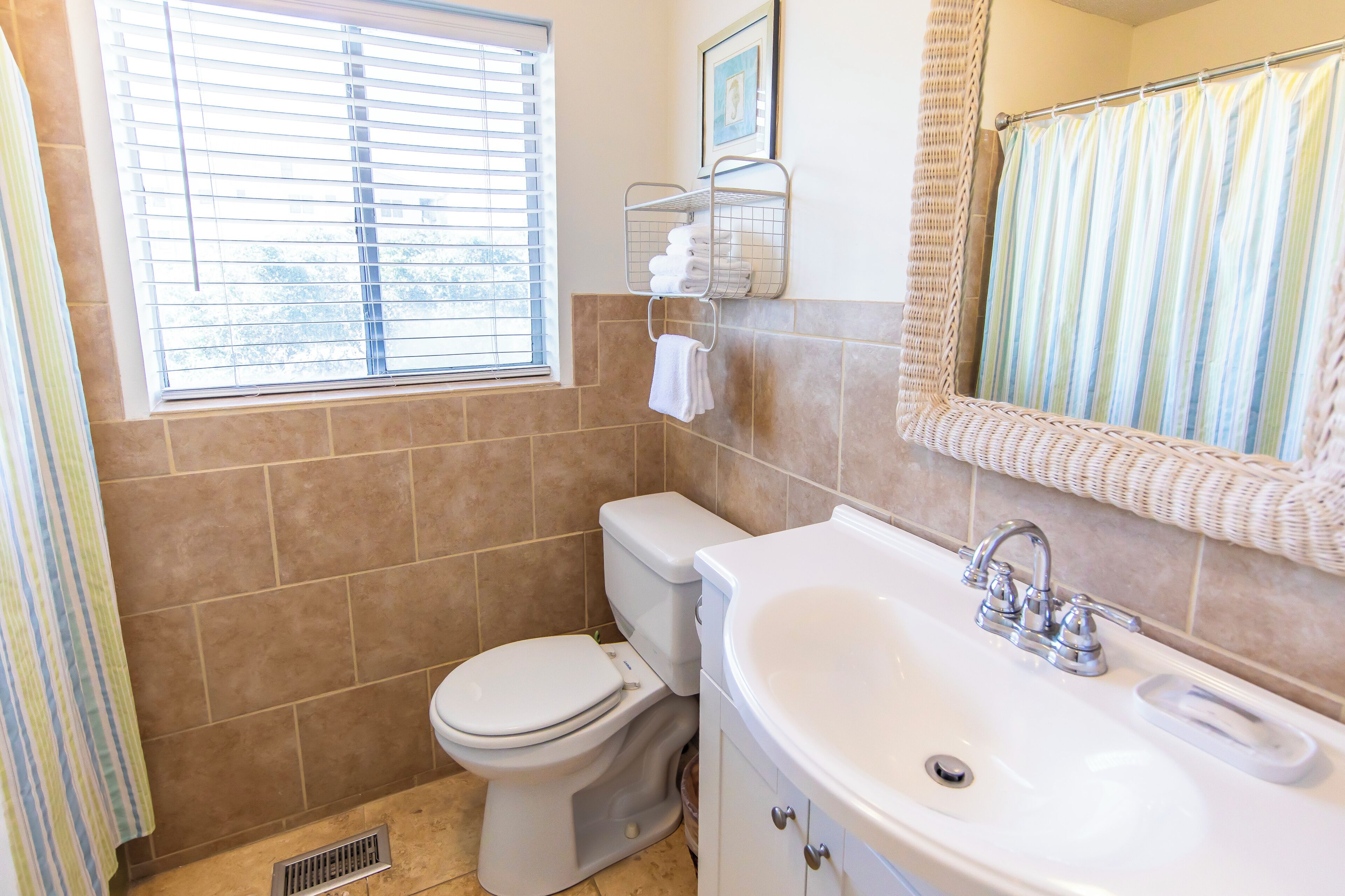 A bathroom with a toilet, sink, and window with blinds.