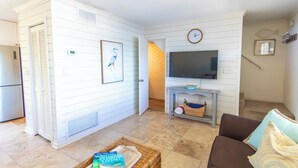 Una sala de estar con televisor, mobiliario de mimbre y un sofá marrón.