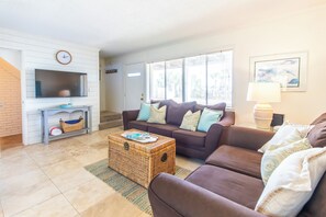 A living room with a flat-screen TV, a sofa set, a coffee table, and a wicker chest.