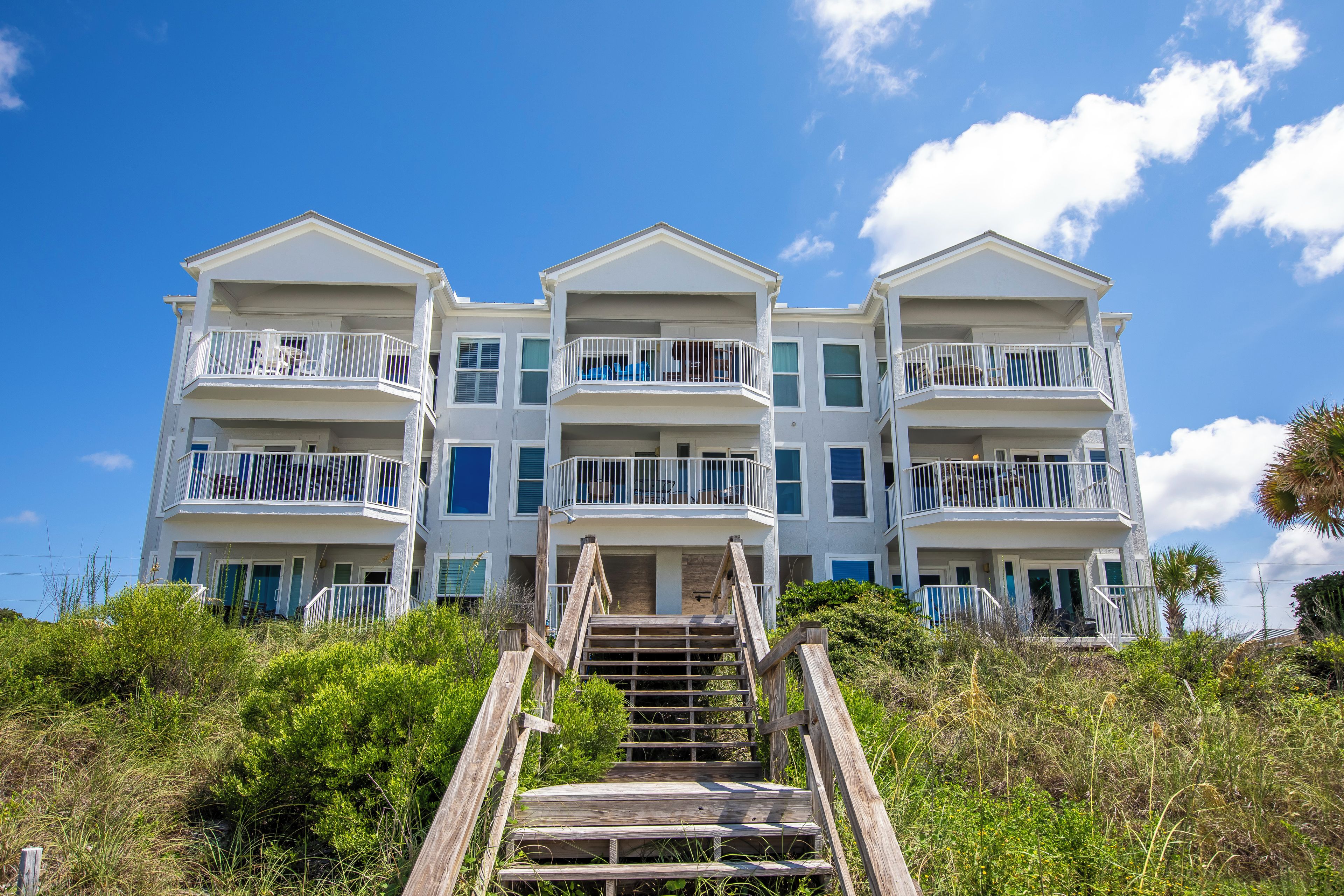 A multi-story building with balconies and a wooden staircase leading up to the entrance.