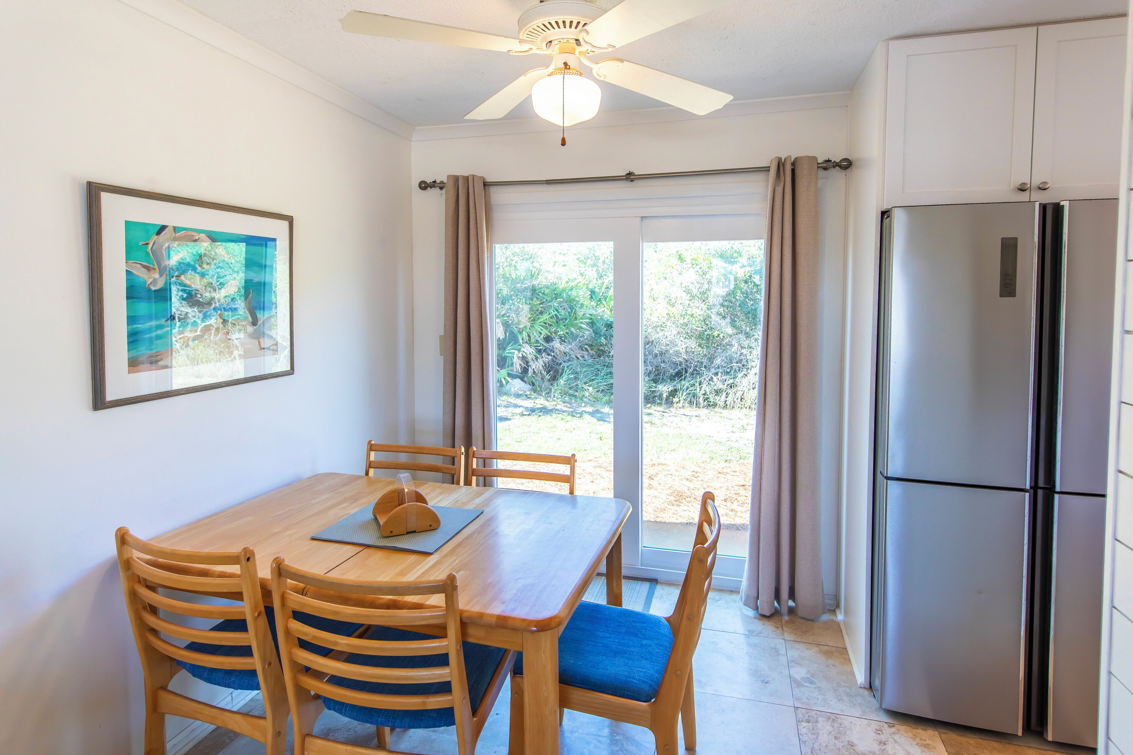 A dining area with a wooden table, chairs, and a ceiling fan.