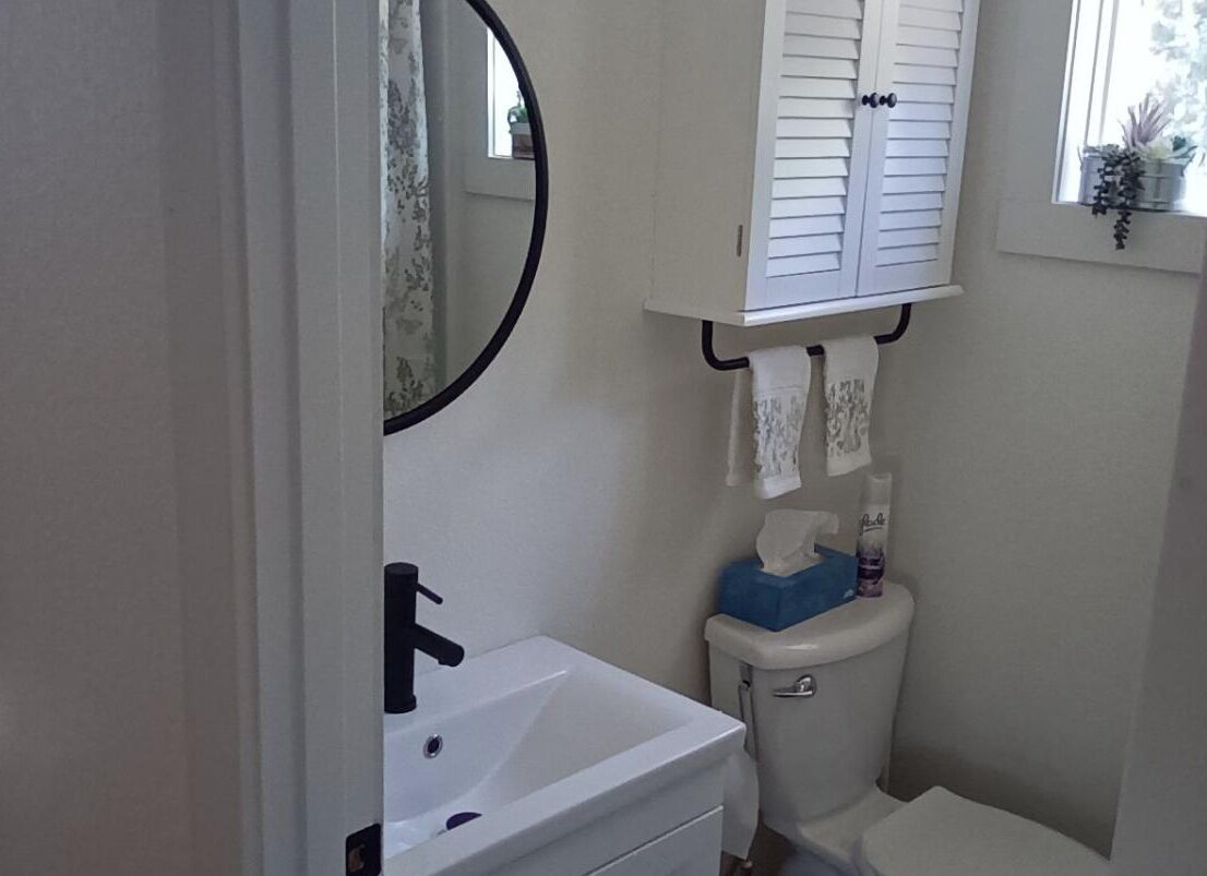 Un baño pequeño con un lavamanos blanco, un inodoro y un espejo.
