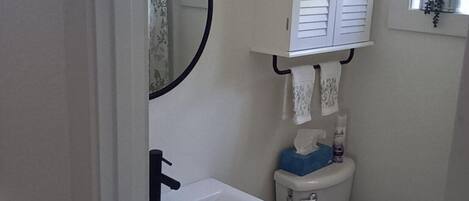 Un baño pequeño con un lavamanos blanco, un inodoro y un espejo.