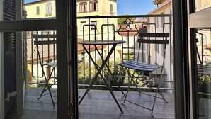 Un balcón con una mesa y sillas, vista a edificios y cielo despejado.