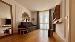 Una sala moderna con un sofá, una mesita de madera, una lámpara de pie y un televisor montado en la pared.
