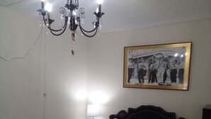 A bedroom with a bed, a nightstand, a lamp, a chandelier, and a framed picture on the wall. - Space Coast Condo in the heart of Titusville (Titusville)