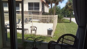 A balcony with a view of a house, a fenced area with chairs, and a potted plant. - Space Coast Condo in the heart of Titusville (Titusville)