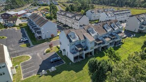 A residential complex with multiple two-story houses, a parking area, and a green landscape. - Spacious 4-bed 3.5-bath Townhome in Long Neck with AC, Swimming Pool & Game Room (Long Neck)