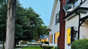 A residential street with two houses, a well-maintained lawn, and a large tree. - NEW! Charming Pet Friendly Modern Cottage in the Historic District of Saugatuck! (Saugatuck)