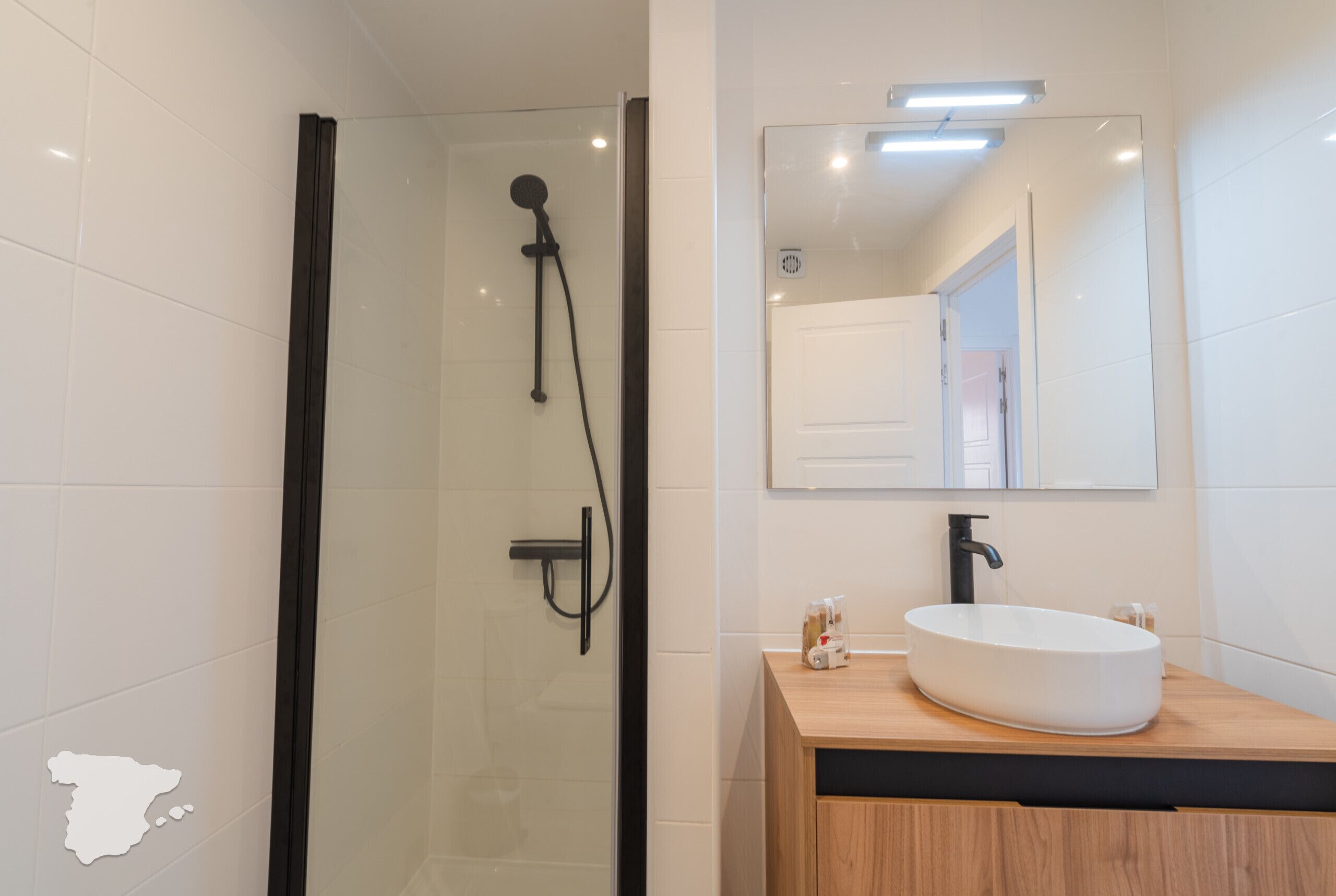 A modern bathroom with a glass-enclosed shower, a wooden vanity with a white sink, and a mirror above the vanity.