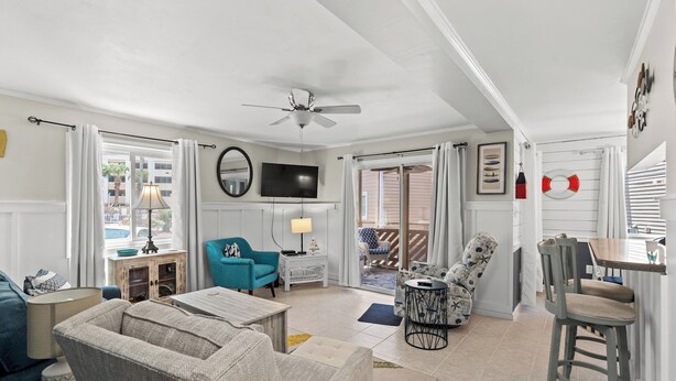 A spacious living room with a ceiling fan, a television, and a dining area with a table and chairs.