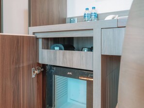 A wooden cabinet with a built-in refrigerator and a microwave. There are two bottles of water on top. - A Hotel Bugis (Singapore)