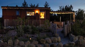 A rustic cabin with a wooden exterior, a small porch, and a garden with rocks and plants. - Romantic Rural Retreat - Rustic Cabin in the Mournes with Private Hot Tub (Annalong)