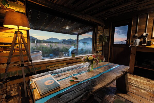 A rustic wooden table with a book, a pen, and a vase with flowers. - Romantic Rural Retreat - Rustic Cabin in the Mournes with Private Hot Tub (Annalong)