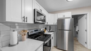 A modern kitchen with white cabinetry, stainless steel appliances, and a tiled backsplash. - Relaxing 2-Bedroom Apartment w / Pool Access (Fort Lauderdale)
