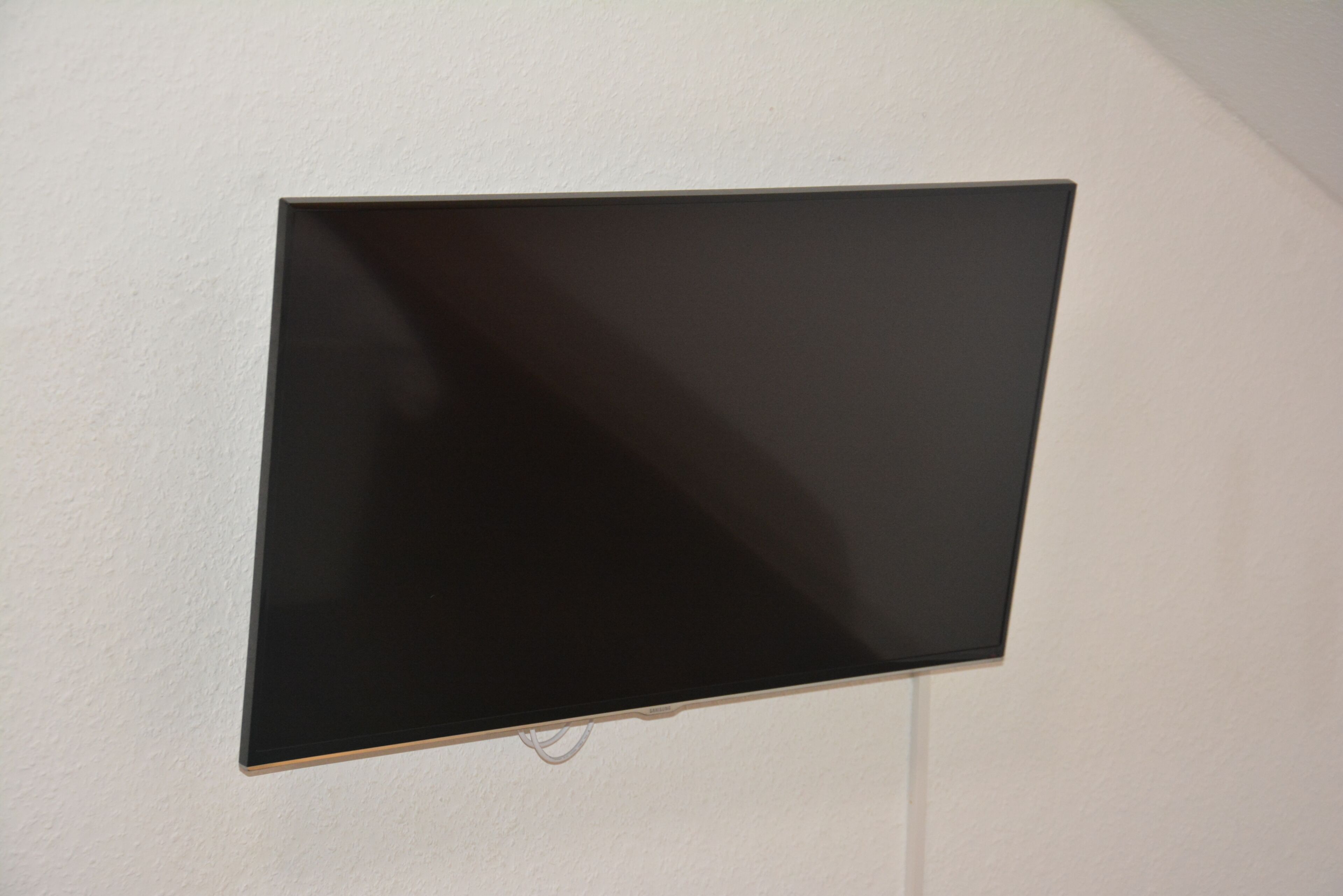 Una televisione a schermo piatto montata su una parete bianca.