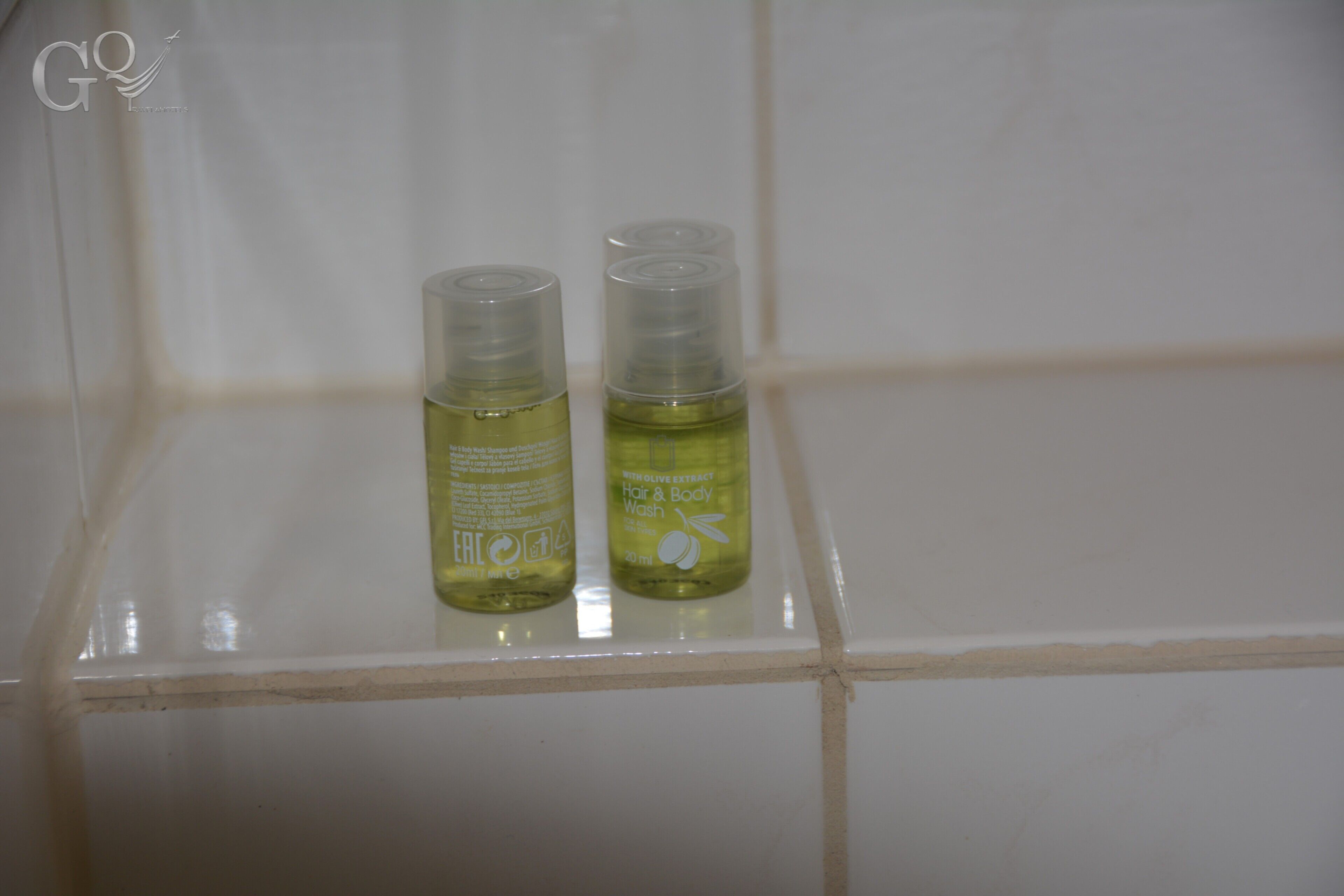 Two bottles of hair and body wash on a tiled shelf.
