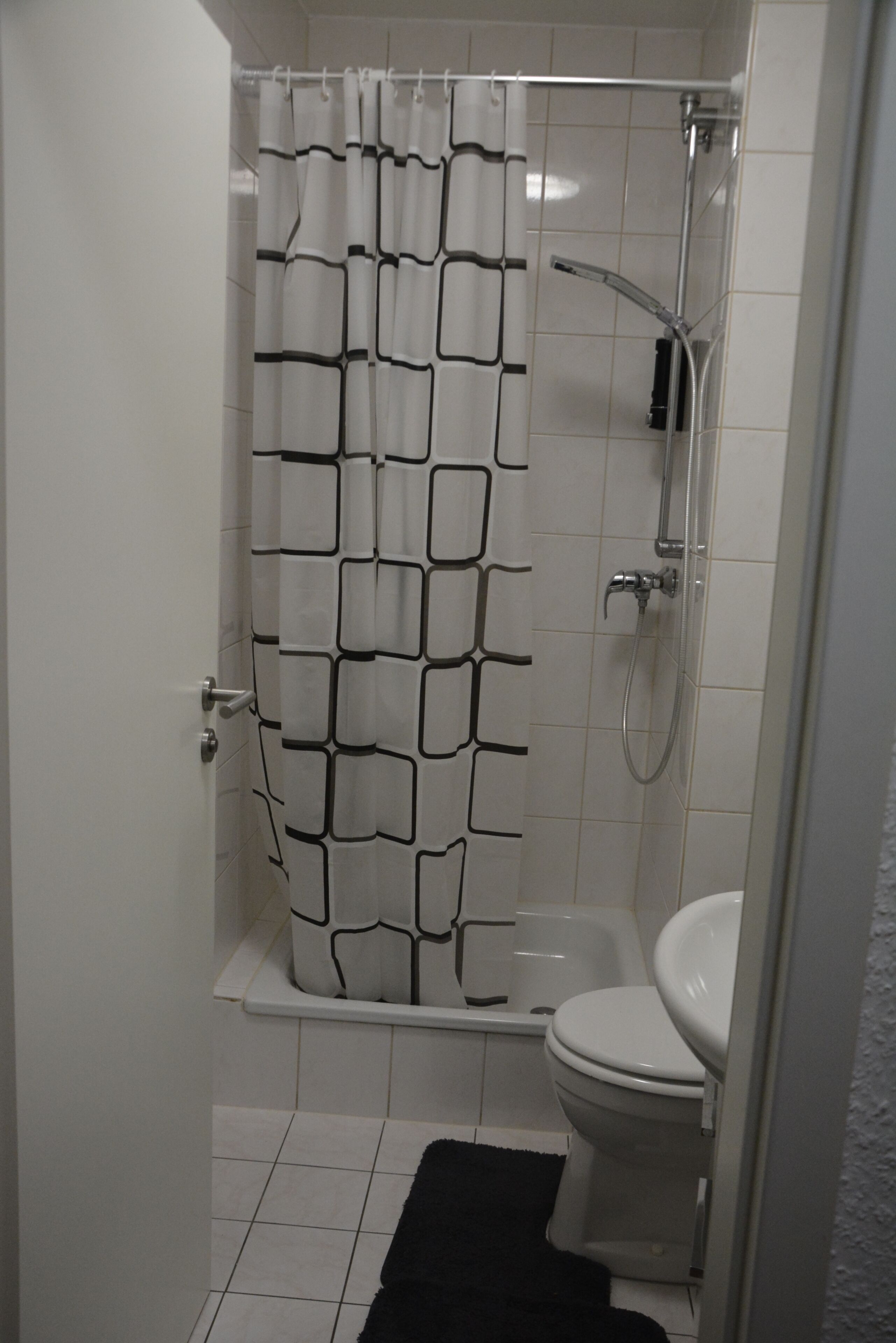 Kylpyhuone, jossa on suihku, wc ja kuviollinen suihkuverho.