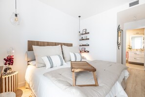 Een moderne slaapkamer met een groot bed, nachtkastjes, een bedlampje en een houten nachtkastje.
