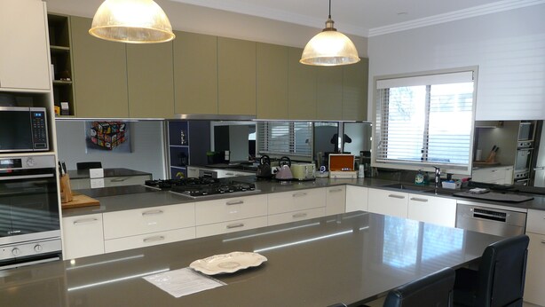 Una cocina moderna con una isla grande, electrodomésticos de acero inoxidable e iluminación colgante.