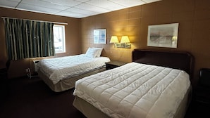 A hotel room with two beds, a window with curtains, a wall-mounted lamp, and a painting. - Grand Inn (Moorhead)