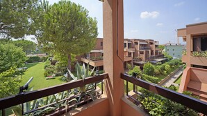 A balcony with a view of a courtyard, including a tree and a building with multiple balconies. - Residence Riviera 43 by Wonderful Italy (Desenzano del Garda)