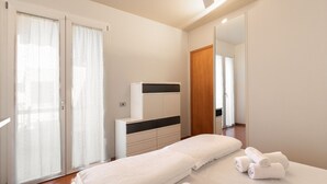A hotel room with a bed, a dresser, a mirror, and a sliding door. - Residence Riviera 43 by Wonderful Italy (Desenzano del Garda)