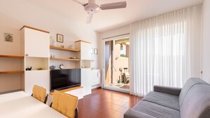 A modern living room with a sofa, TV, and built-in shelves. - Residence Riviera 43 by Wonderful Italy (Desenzano del Garda)