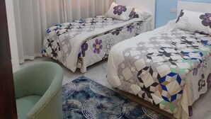 A bedroom with two beds, a chair, a patterned rug, and a painting on the wall. - Sea View Chic Apartment in Sharm (Sharm El Sheikh)