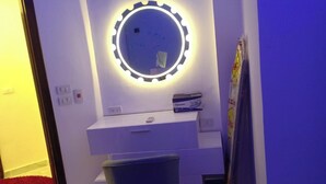 A bathroom with a vanity, a mirror with lights, a towel rack, and a trash bin. - Sea View Chic Apartment in Sharm (Sharm El Sheikh)