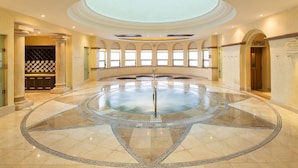 Un jacuzzi circular con un poste central, rodeado por un suelo de baldosas con un diseño geométrico.